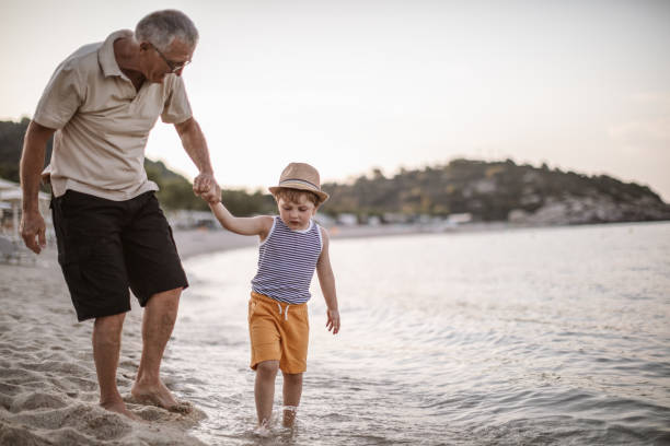 istock Grandfather with grandson walking at the beach 1200520911