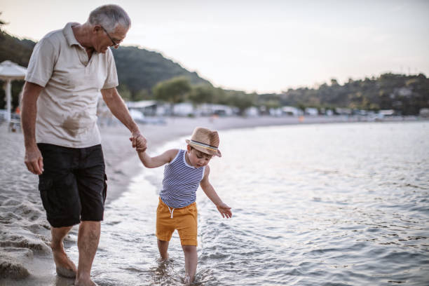 istock Grandfather with grandson walking at the beach 1200521803