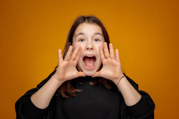 teenage girl scream shout in theatrical gesture with mouth wide open and both hands by the face stock photo