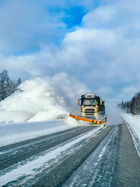 Winter service truck for snow plow clearing road after winter snowstorm in Finland.