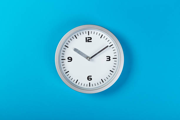 istock minimalistic white wall clock with light metal on a blue background. time concept. 1200528964