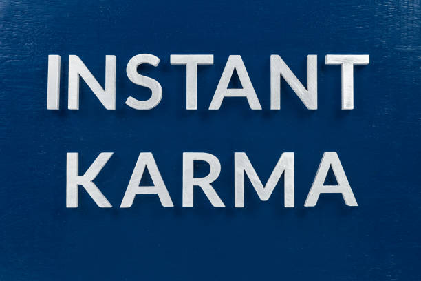 the phrase instant karma laid with silver metal letters on classic blue painted board background