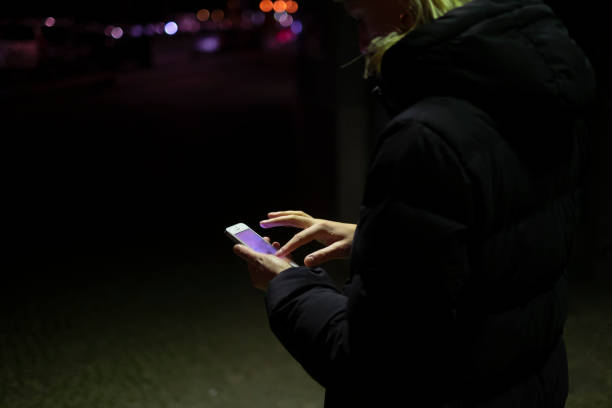 istock Business woman using smartphone outdoors at night 1200530850