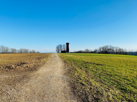 Rural street and meadows in January, observation tower in background