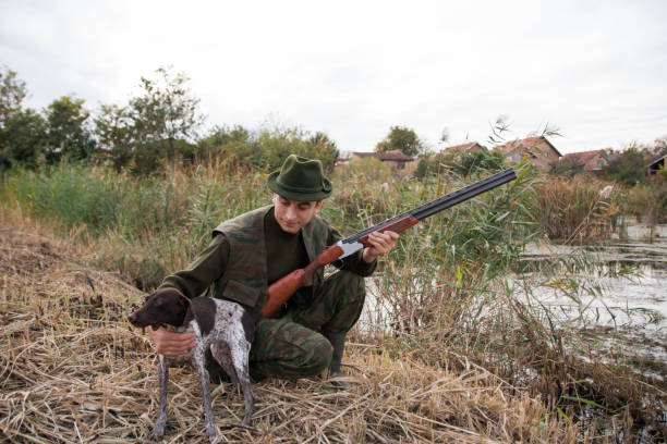 istock Hunter wearing green suit and hat holding with one hand his hunter dog 1200531135