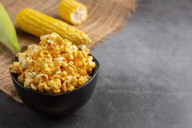 istock Popcorn in the black bowl and raw corn on the black cement floor. 1200533120
