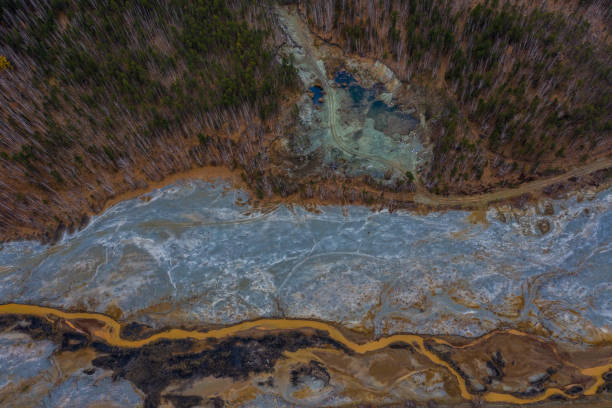 istock Aerial view drone flying forward over polluted river with destroyed ecosystem and copper tailing dump poisoning ground and water air emissions from industry environmental disaster in South Ural 1200541727