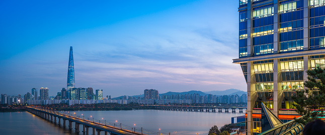 Panoramic view across the Han River to the futuristic highrise cityscape of the Jamsil district of central Seoul, South Korea’s vibrant capital city at sunset.