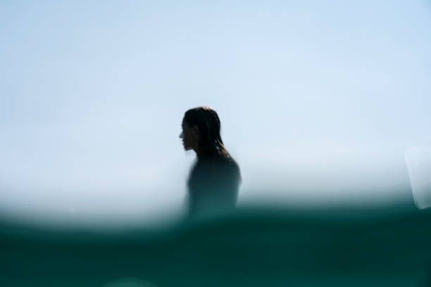 Silhouette surf girl defocused A silhouette of a young woman in a wetsuit on the water horizon, New Zealand mount maunganui stock pictures, royalty-free photos & images