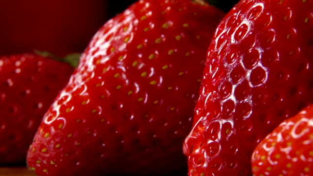 Strawberries with drop of water flowing over surface