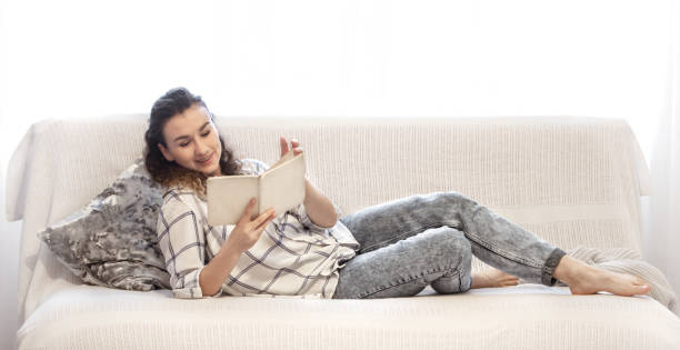 istock Woman reading a book on the couch. 1200548362