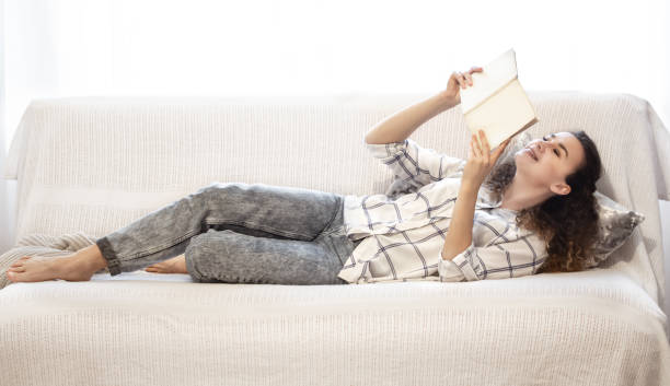 istock Woman reading a book on the couch. 1200548400