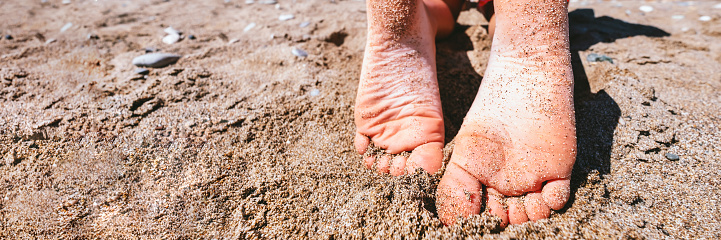 Young girls legs on beach. Summertime relax. Womans or kids feet on beach. Vacation travel concept. Happy people. Banner with copyspace. Stock photo.