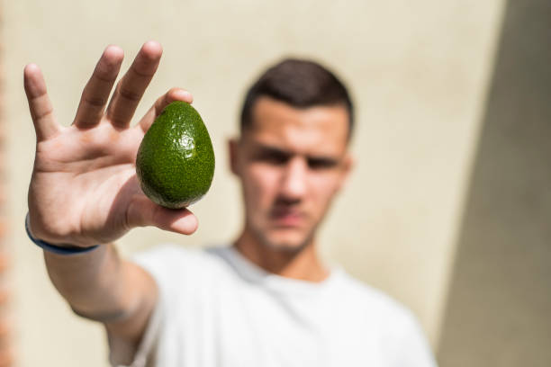young man with an avocado in his hand and unfocused background