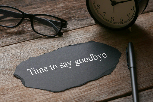 Gafas, reloj, bolígrafo y un pedazo de papel negro escrito con tiempo para decir adiós sobre fondo de madera. photo