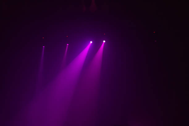 istock A group pink rays from spotlights on a dark background on a concert show 1200554404