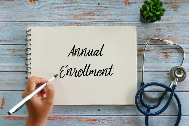 Top view of plant,stethoscope, and hand writing Annual Enrollment on notebook on wooden background. stock photo
