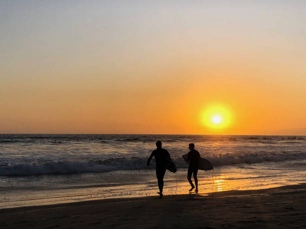 サーファーは南カリフォルニアのヴェネツィアの太平洋で一日の最後の時間を楽しむ - santa monica surfing beach city of los angeles ストックフォトと画像