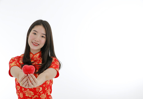 the young asian little woman wearing Chinese traditional dress wish luck and holding small red heart Valentine and new year on isolated white background copy space