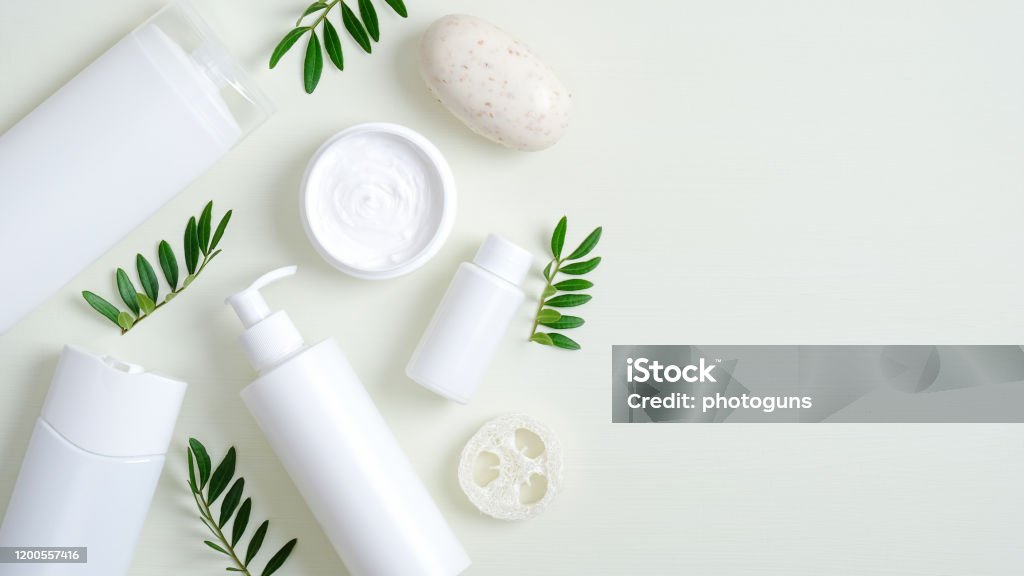 Organic herbal cosmetic products on green background. Top view beauty spa cosmetic bottle packaging, hand cream, lotion, bath sponge, natural soap and green leaves. Minimalist beauty product mockups Merchandise Stock Photo