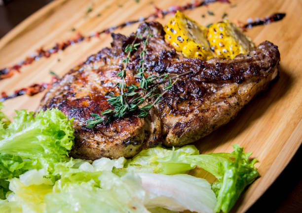 costillas de cerdo a la parrilla con maíz y ensalada sobre una tabla de madera. - rubbing spice rib barbecue fotografías e imágenes de stock