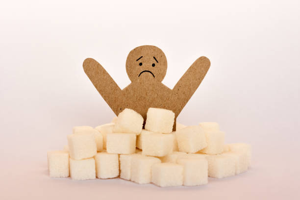 Sugar addiction, insulin resistance, unhealthy diet, figure of a cardboard man surrounded by refined sugar cubes on white background, diabetes protection medical concept Sugar addiction, insulin resistance, unhealthy diet, figure of a cardboard man surrounded by refined sugar cubes on white background, diabetes protection medical concept glycogen stock pictures, royalty-free photos & images