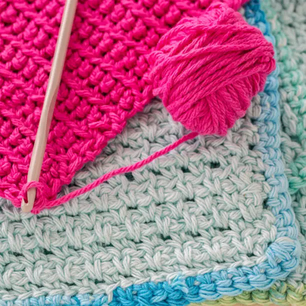 Crocheted dishcloths, with a hook and a ball of yarn.