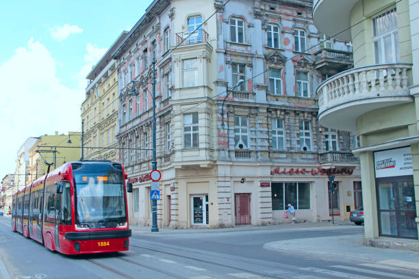 Lodz / Poland. 20 July 2019: Modern tram going through street in Poland. Modern tram riding around city. Red tram going on city street in Lodz