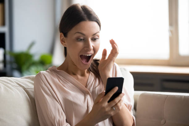 istock Amazed girl shocked by online win on cell 1200561565