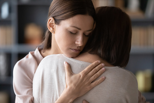 Sad adult daughter hug comfort middle-aged mother make peace reconcile after fight, upset distressed grown-up female embrace caress senior mom show love and care at home, parenting concept