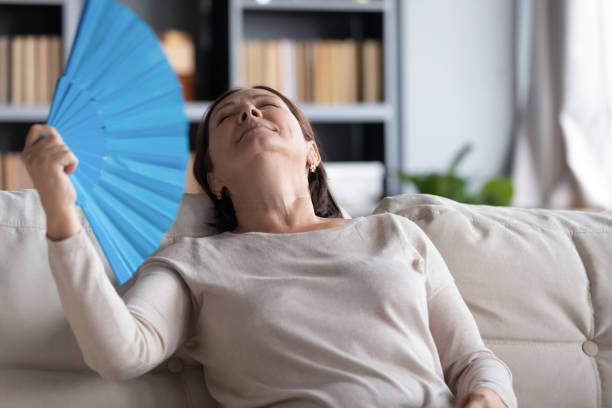 mujer mayor sobrecalentada relajarse usando ventilador de mano - menopausia fotos fotografías e imágenes de stock