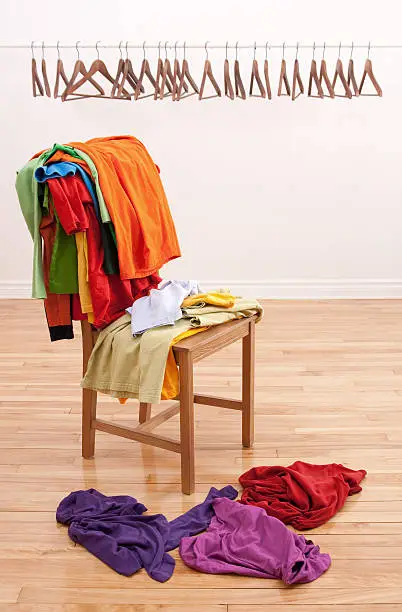 Photo of Messy clothes on a chair and empty hangers