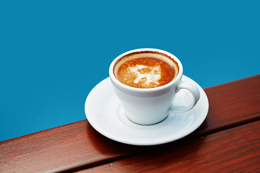 Cup of coffee espresso on a table over blue background