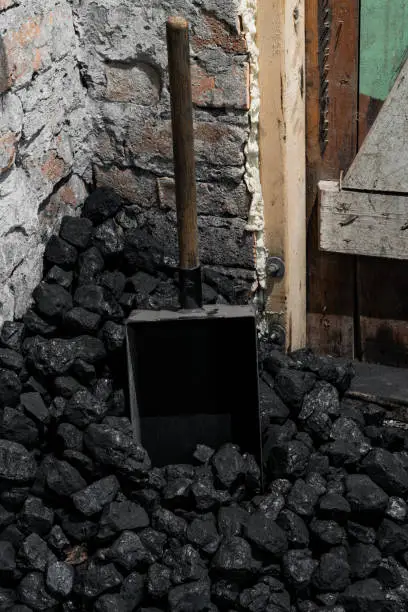 Photo of A coal shovel stuck in a pile of coalat the basement prepared for heating the house with.
