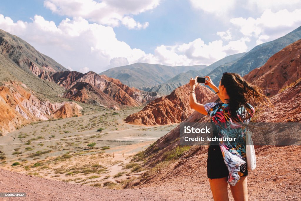 Tourist woman photographing the mountains of Argentina Young tourist woman photographing the beauty of the mountains in Purmamarca, Jujuy, Argentina. Salta - City Stock Photo
