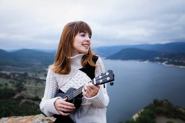 istock young woman plays ukelele in nature and laughs 1200572490