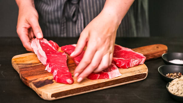 istock Raw New York strip steaks on a wood cutting board. 1200575668