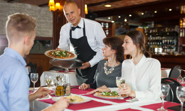 istock Waiter bringing pizza to guests 1200577661