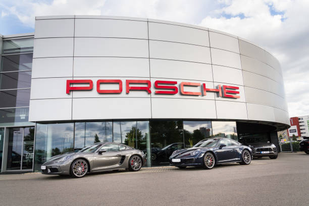 Porsche logo on car in front of dealership building stock photo