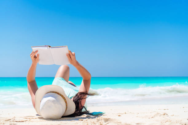 istock Woman with book on the seashore lying 1200580785