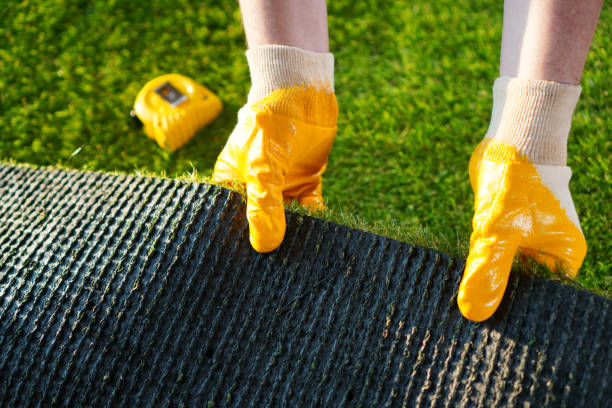 istock Greenering with the green artificial grass background. Worker holds a roll of green artificial turf. 1200580829