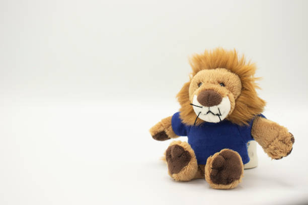 Stuffed toy lion in blue tshirt stretching arm out.