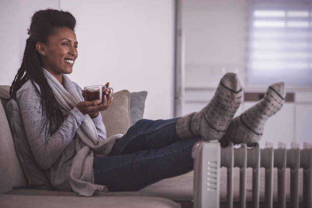 Woman drinking hot tea, heating feet at home.