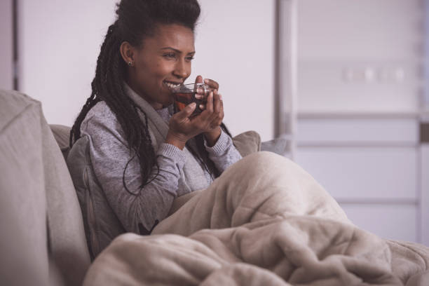istock Woman drinking hot tea, comfortable sitting on a couch. 1200584081
