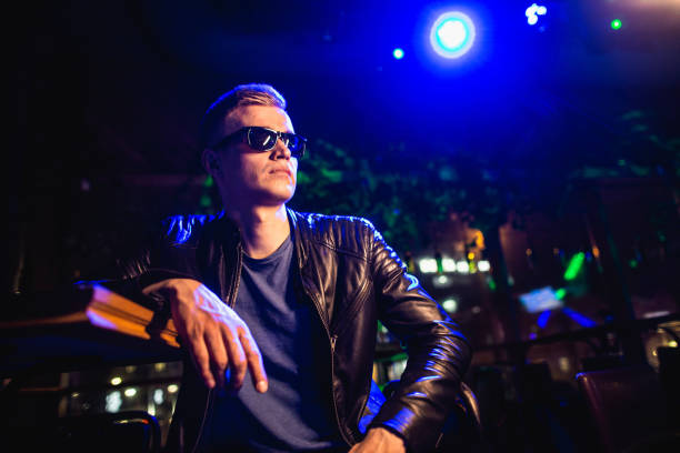 istock Handsome man in leather jacket with sunglasses and neon lights 1200587266
