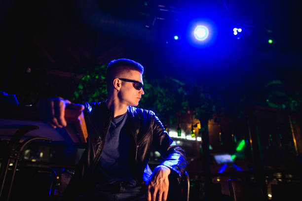 istock Handsome man in leather jacket with sunglasses and neon lights 1200587275