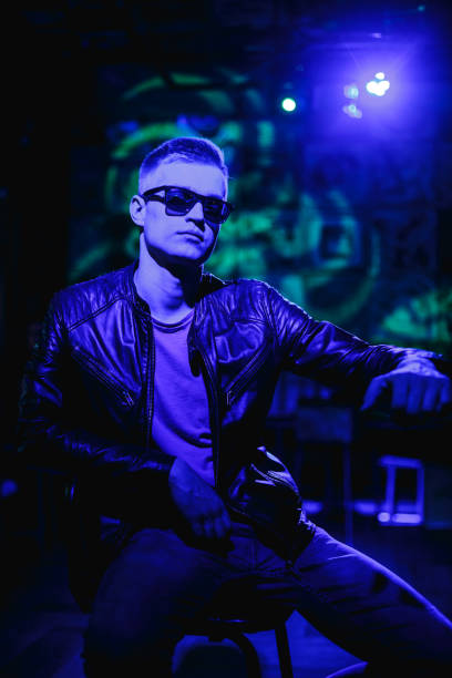 istock Handsome man in leather jacket with sunglasses and neon lights 1200587276