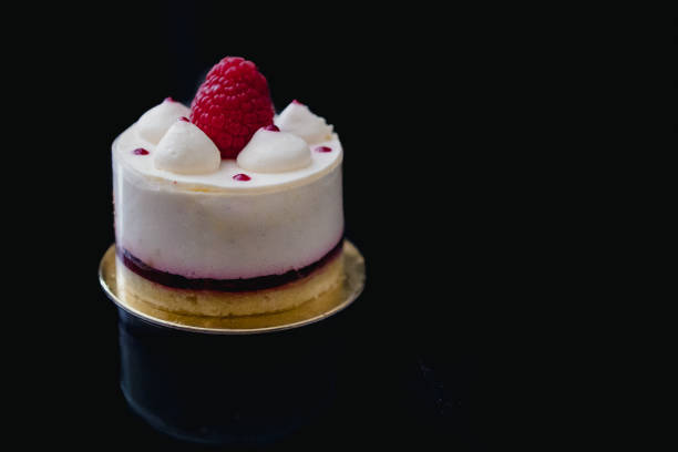istock Luxury white cheesecake mousse cake decorated with fresh raspberries on a dark background. Flat lay. Close-up. Copy space 1200588693