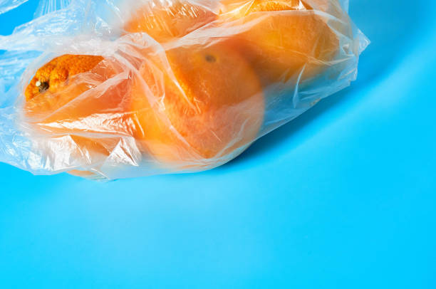 istock Fresh whole mandarins or oranges in polietilene bag on blue background. Fruit purchasing concept. Space for text 1200593949