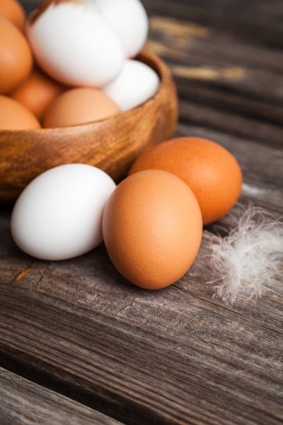 White and brown chicken eggs on wooden background stock photo